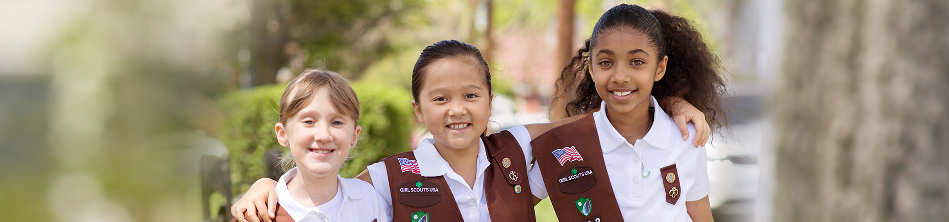  Three Girl Scouts smiling in the woods while hiking. 