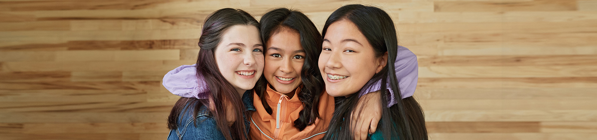  The Cadette Girl Scouts with their arms around each other smiling at the camera 