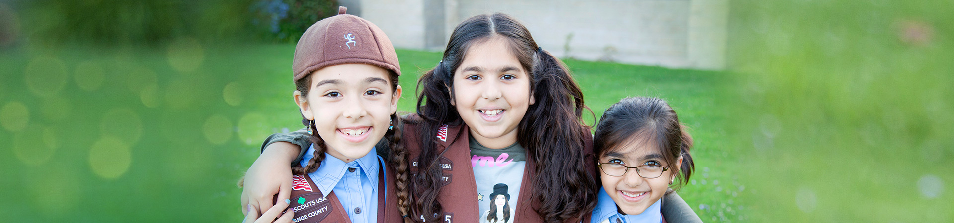  Three Brownie Girl Scouts with their arms around each other smiling at the camera 