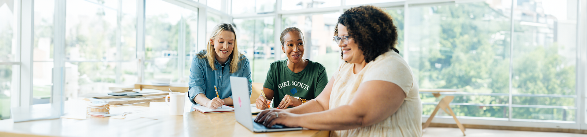  Three volunteers sitting at a table working on something 